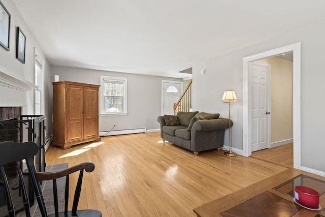 living room with baseboards, a fireplace, stairs, light wood-style floors, and baseboard heating