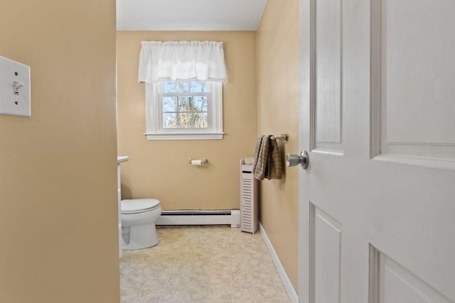 bathroom with a baseboard heating unit, toilet, and baseboards