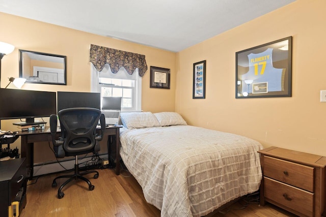 bedroom featuring baseboard heating and wood finished floors