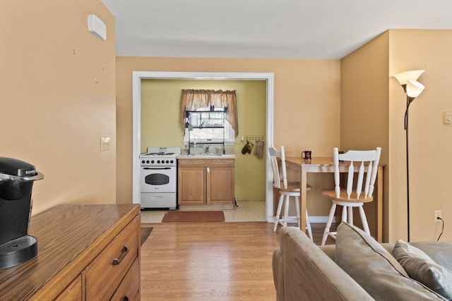 kitchen with white electric stove, brown cabinets, light wood-style floors, and a sink