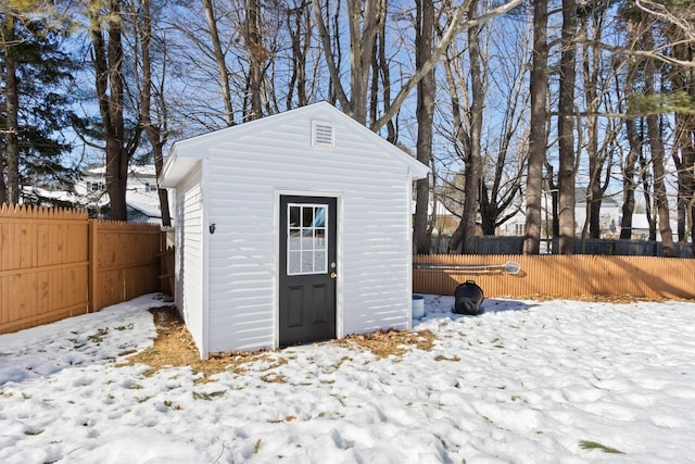 snow covered structure featuring an outbuilding, fence private yard, and a storage shed