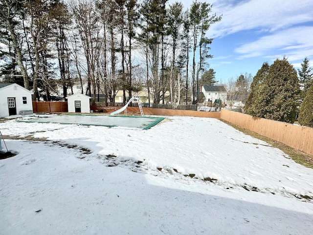 yard covered in snow featuring an outbuilding, a shed, and a fenced backyard