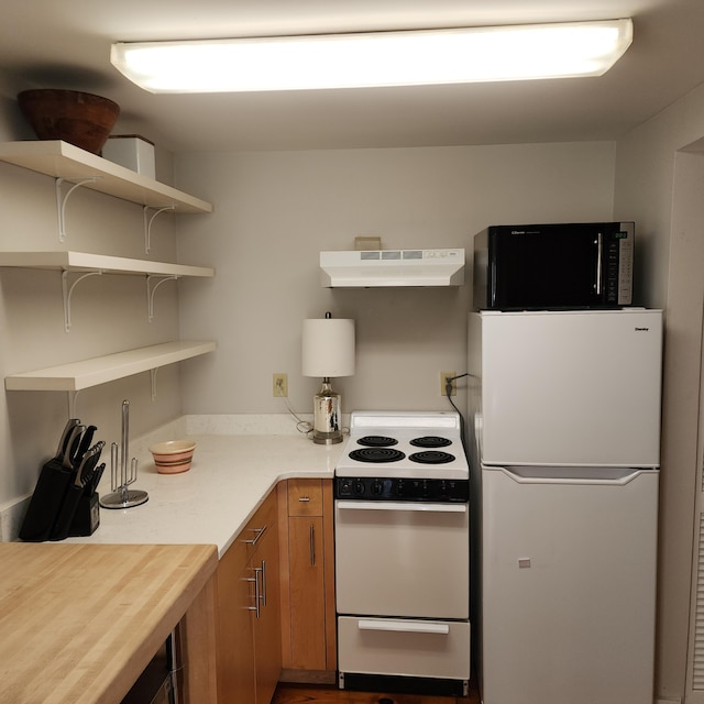 kitchen with under cabinet range hood, white appliances, light countertops, open shelves, and brown cabinetry