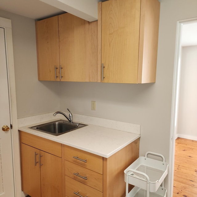 kitchen with light countertops, light brown cabinetry, a sink, and light wood-style floors