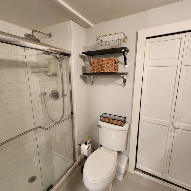 bathroom featuring a stall shower, tile patterned flooring, and toilet