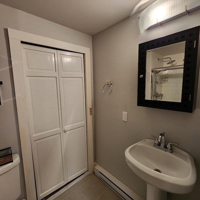 bathroom featuring a baseboard radiator, toilet, a sink, a tile shower, and tile patterned floors