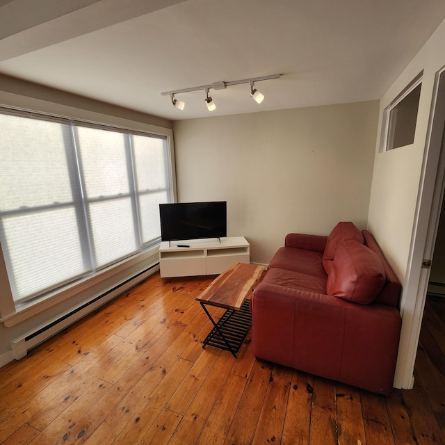 living room with a baseboard heating unit, wood-type flooring, and track lighting