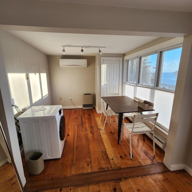 laundry area with washer / dryer, laundry area, baseboards, hardwood / wood-style flooring, and an AC wall unit