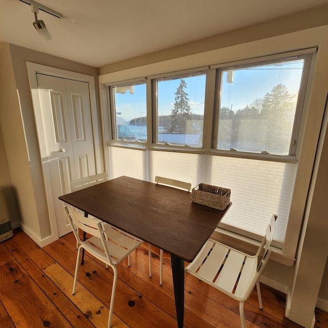 dining room featuring a water view, hardwood / wood-style flooring, and baseboards