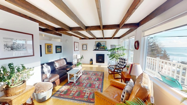 living area with a fireplace, beamed ceiling, and wood finished floors