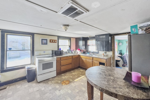 kitchen featuring white range with electric stovetop, visible vents, brown cabinets, and a sink