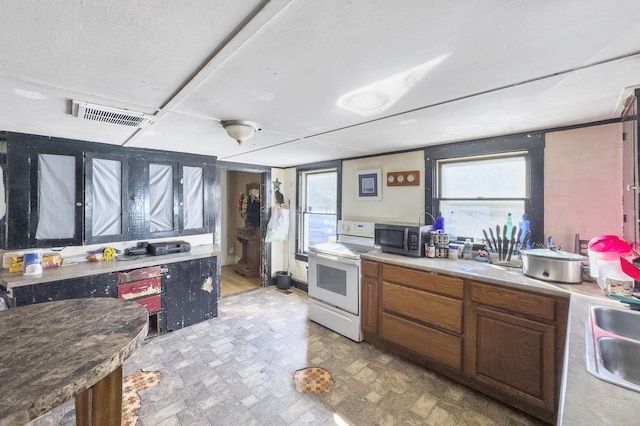 kitchen with a sink, visible vents, light countertops, white range with electric stovetop, and stainless steel microwave