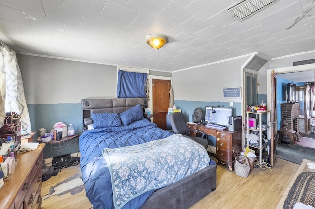 bedroom with visible vents, crown molding, and wood finished floors