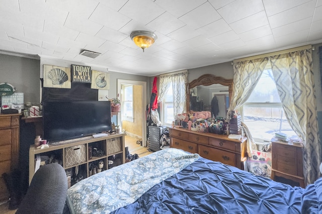 bedroom featuring visible vents, wood finished floors, and ornamental molding