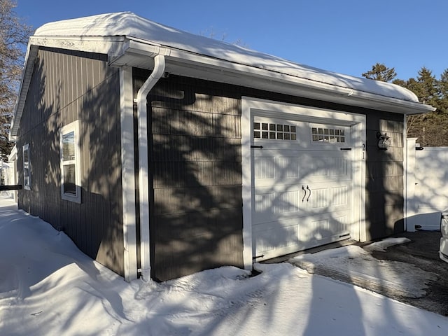 view of snow covered exterior featuring a garage and an outdoor structure