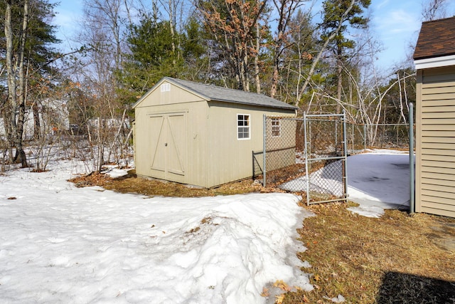 snow covered structure featuring a shed and an outdoor structure