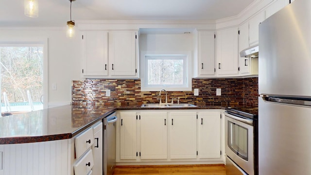 kitchen featuring a peninsula, backsplash, appliances with stainless steel finishes, and a sink