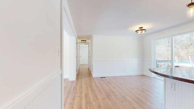 unfurnished dining area with light wood-type flooring and wainscoting