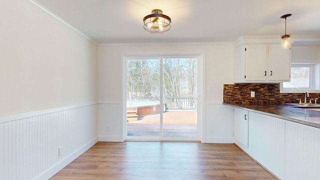 interior space featuring dark countertops, ornamental molding, light wood finished floors, and a sink