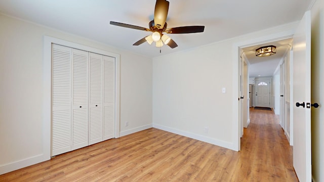 unfurnished bedroom featuring ceiling fan, baseboards, ornamental molding, light wood-style flooring, and a closet