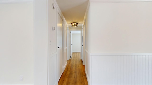 corridor featuring a wainscoted wall and light wood-style flooring