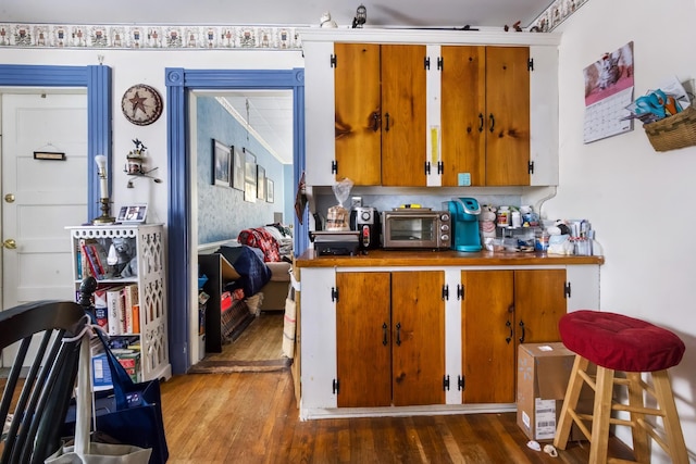 kitchen with a toaster, brown cabinets, and wood finished floors