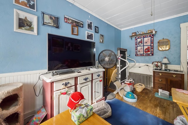 bedroom featuring a wainscoted wall, radiator heating unit, hardwood / wood-style flooring, and crown molding