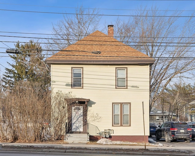 view of front of property with a shingled roof and a chimney