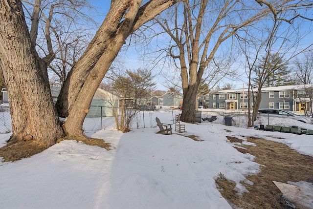 yard covered in snow with fence and a residential view