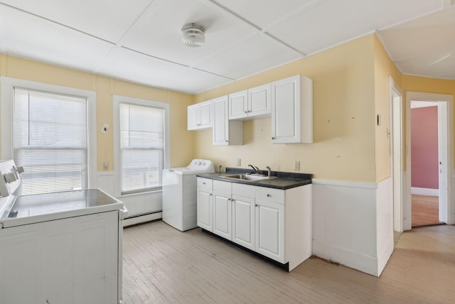 kitchen featuring a baseboard radiator, washer / clothes dryer, a sink, light wood-style floors, and wainscoting