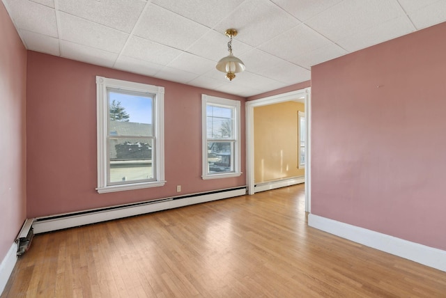 unfurnished room featuring a drop ceiling, wood finished floors, baseboards, and baseboard heating