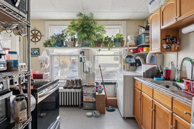 kitchen with brown cabinets, a sink, washer / clothes dryer, radiator, and appliances with stainless steel finishes