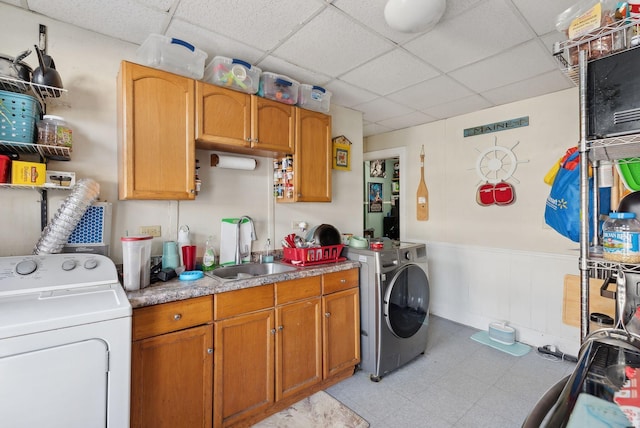 laundry area featuring washer and clothes dryer, cabinet space, light floors, and a sink