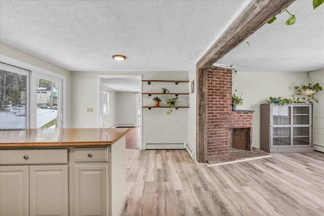 kitchen with light wood-style flooring, a fireplace, and a textured ceiling