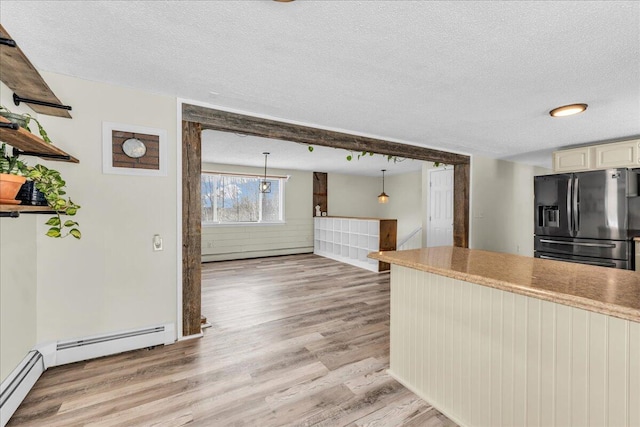 kitchen featuring light wood finished floors, open shelves, baseboard heating, a textured ceiling, and black fridge