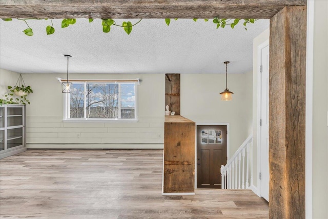 interior space featuring a textured ceiling, a baseboard heating unit, and wood finished floors