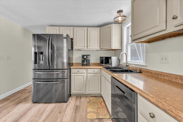 kitchen with stainless steel appliances, light wood-style flooring, a sink, and light countertops