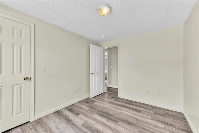 unfurnished bedroom featuring baseboards, a textured ceiling, and light wood-style floors