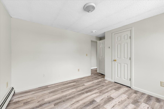 unfurnished bedroom featuring light wood-style floors, baseboards, a textured ceiling, and baseboard heating