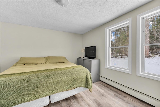 bedroom featuring a textured ceiling, light wood finished floors, and baseboard heating