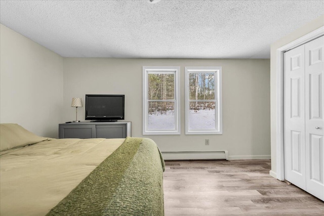 bedroom with a baseboard radiator, a closet, a textured ceiling, and wood finished floors