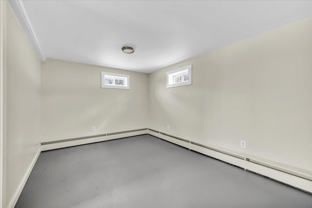 spare room with a baseboard radiator, finished concrete flooring, and baseboards