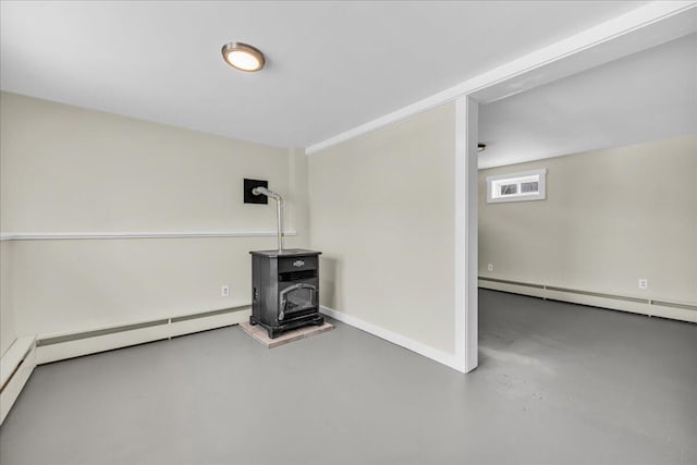 interior space with a baseboard heating unit, a wood stove, and baseboards