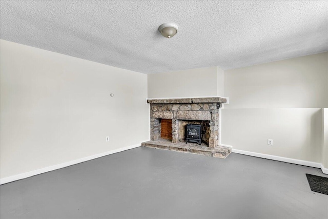 unfurnished living room featuring finished concrete flooring, baseboards, and a textured ceiling