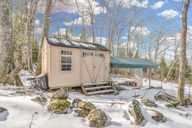 snow covered structure featuring an outbuilding, a storage shed, and entry steps