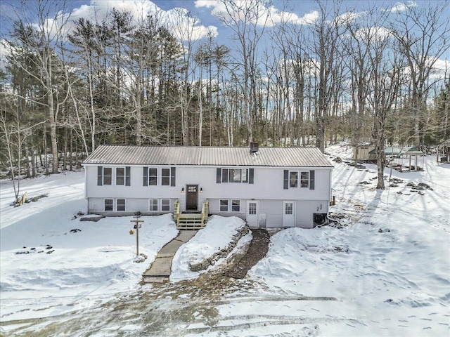 split foyer home with a garage, a chimney, and metal roof