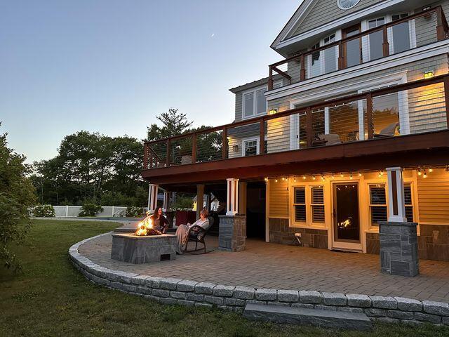 rear view of house featuring a patio area, fence, a fire pit, and a yard