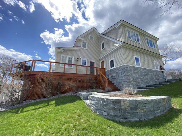 back of house featuring stairway, a deck, and a yard