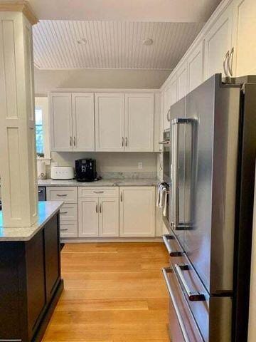 kitchen with light wood-style floors, white cabinetry, light countertops, and high end fridge