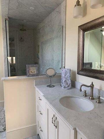 bathroom featuring a tile shower and vanity